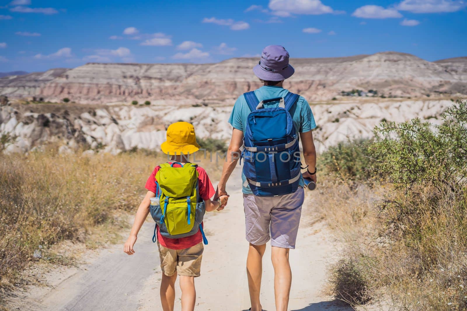 Father and son tourists exploring valley with rock formations and fairy caves near Goreme in Cappadocia Turkey.