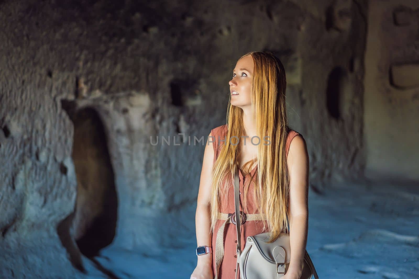 Young woman exploring valley with rock formations and fairy caves near Goreme in Cappadocia Turkey.