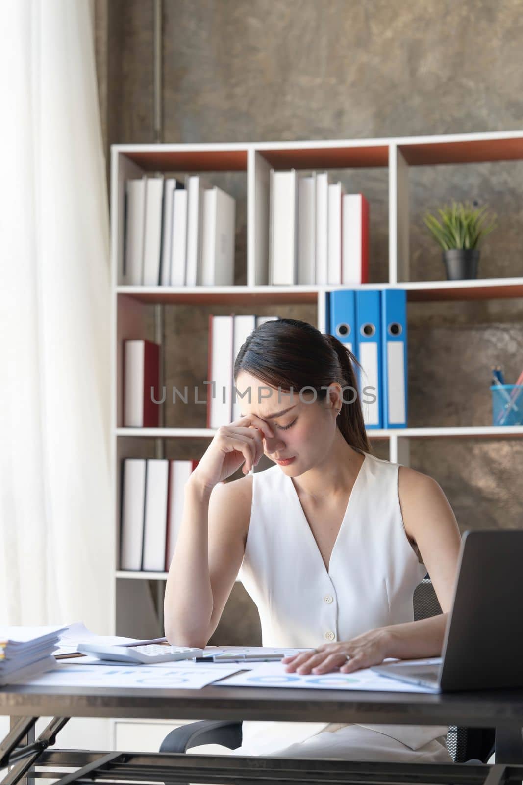 Young Business Asian women are stressed while working on laptop, Tired asian businesswoman with headache at office, feeling sick at work copy space in workplace an home office. by wichayada