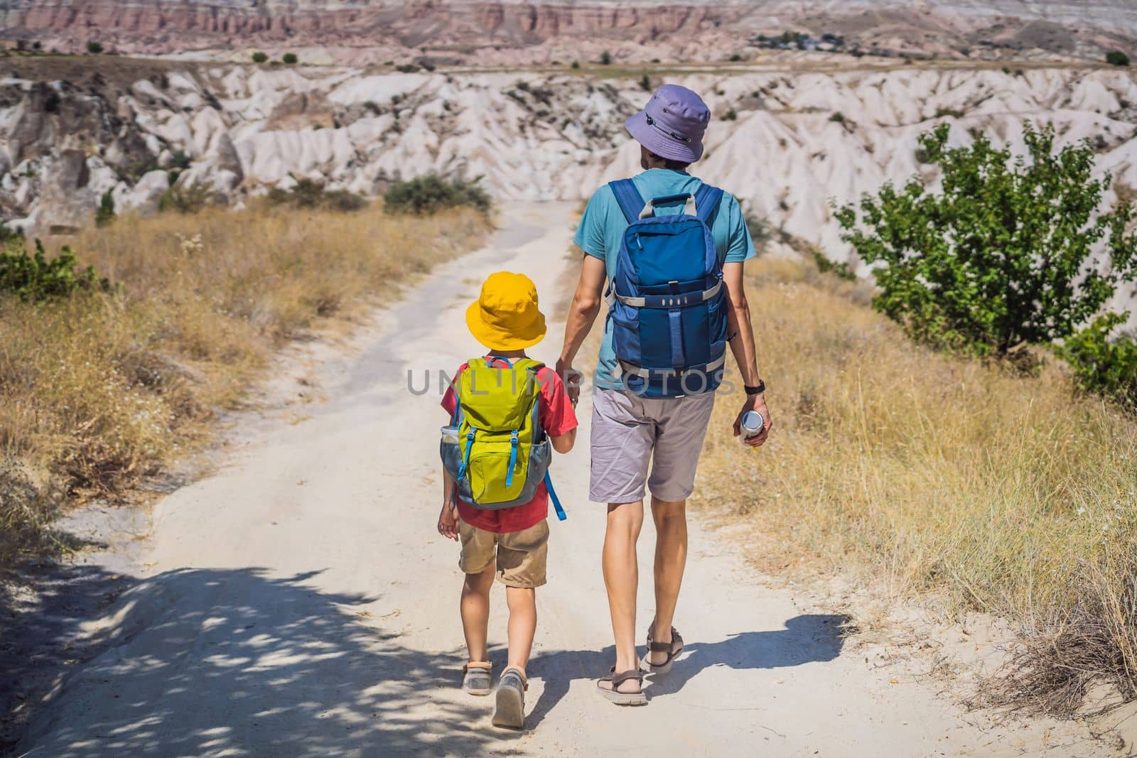 Father and son tourists exploring valley with rock formations and fairy caves near Goreme in Cappadocia Turkey.