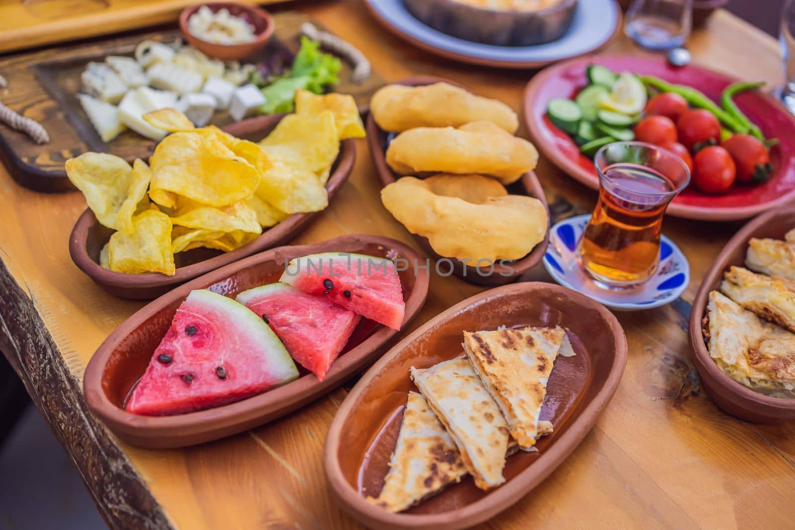 Turkish breakfast table. Pastries. Vegetables. Olives. Cheeses, fried eggs. Jams, tea in copper pot and tulip glasses. Wide composition.