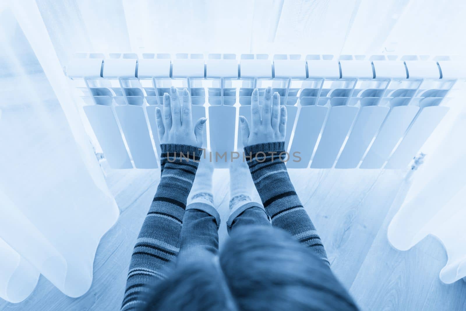 Girl warms up the frozen hands above hot radiator, close up