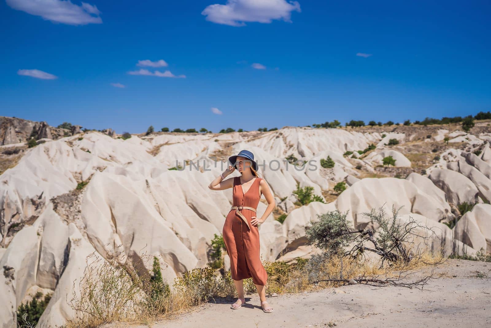 Young woman exploring valley with rock formations and fairy caves near Goreme in Cappadocia Turkey.