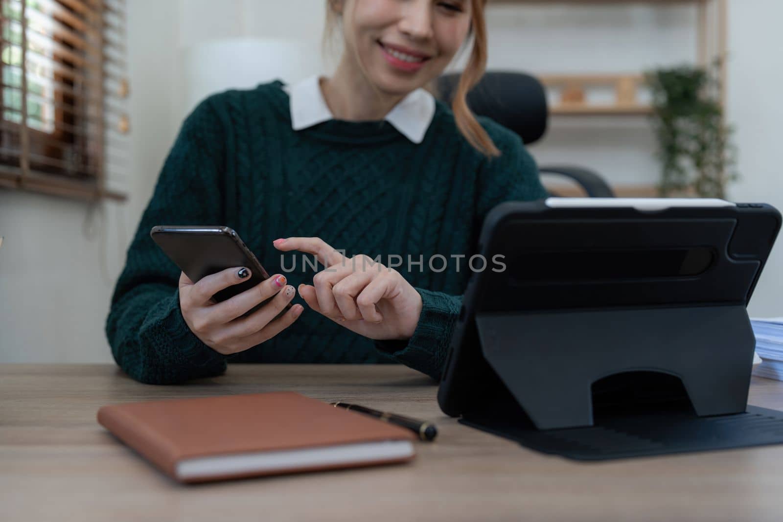 Close up Business woman using calculator and phone for do math finance on wooden desk in office and business working background, tax, accounting, statistics and analytic research concept.