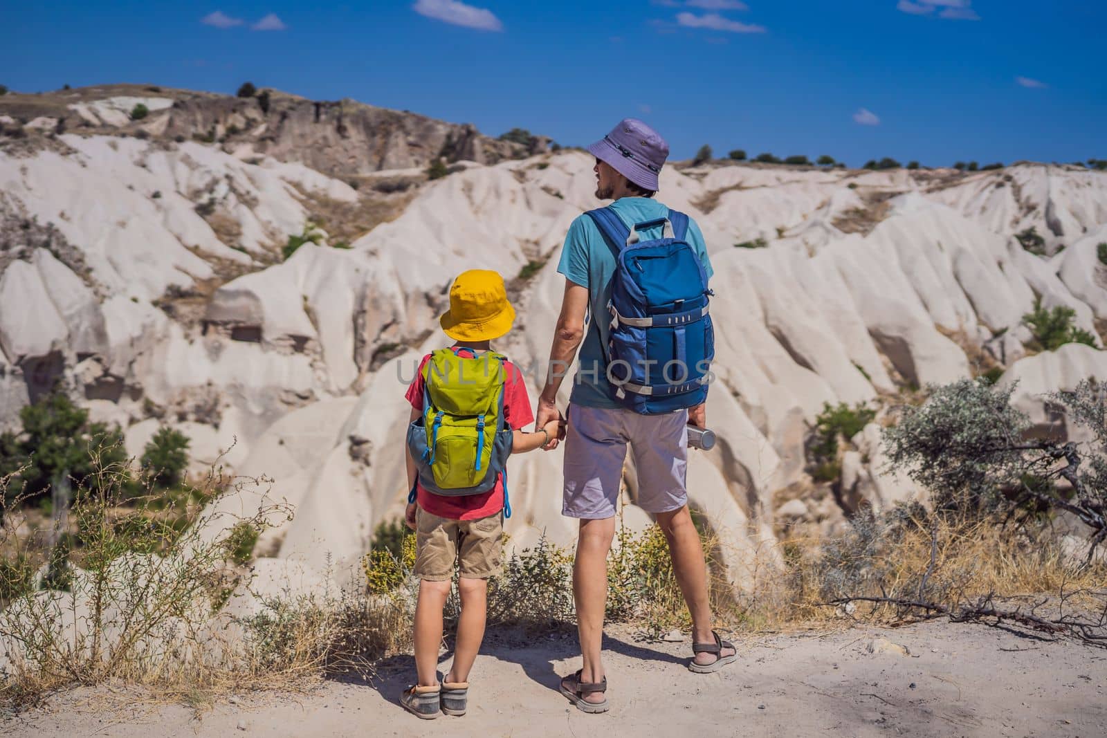 Father and son tourists exploring valley with rock formations and fairy caves near Goreme in Cappadocia Turkey.