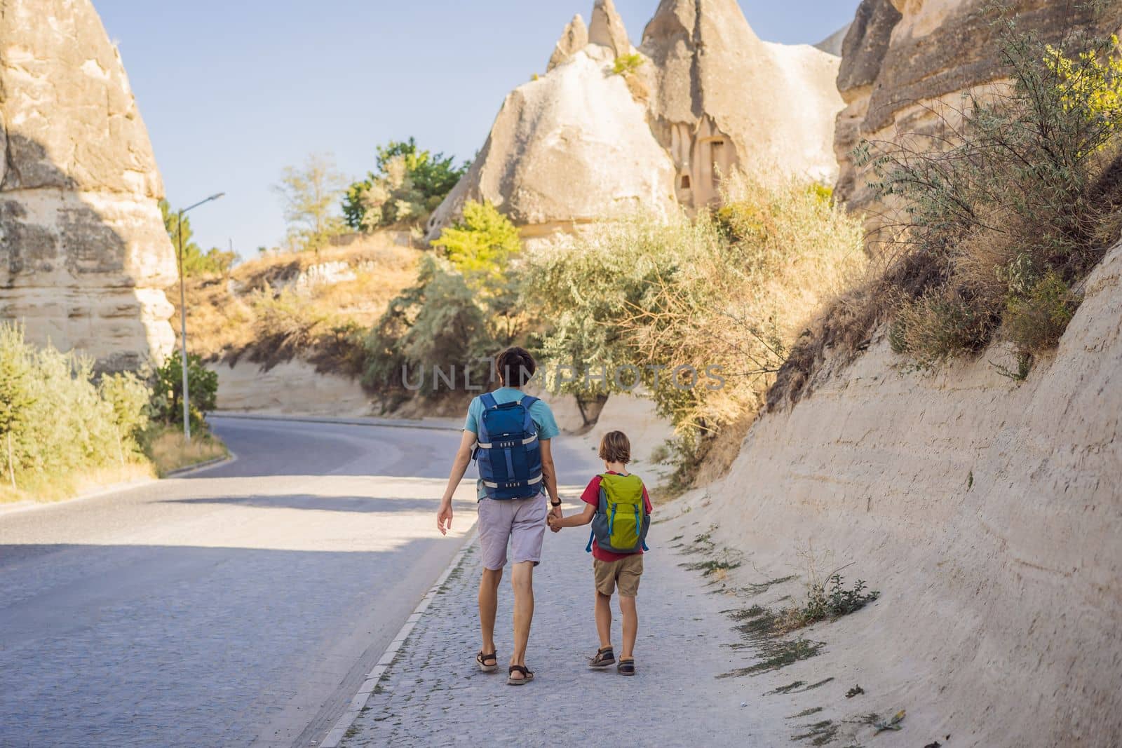 Father and son tourists on background of Unique geological formations in Love Valley in Cappadocia, popular travel destination in Turkey. Traveling with children in Turkey concept.