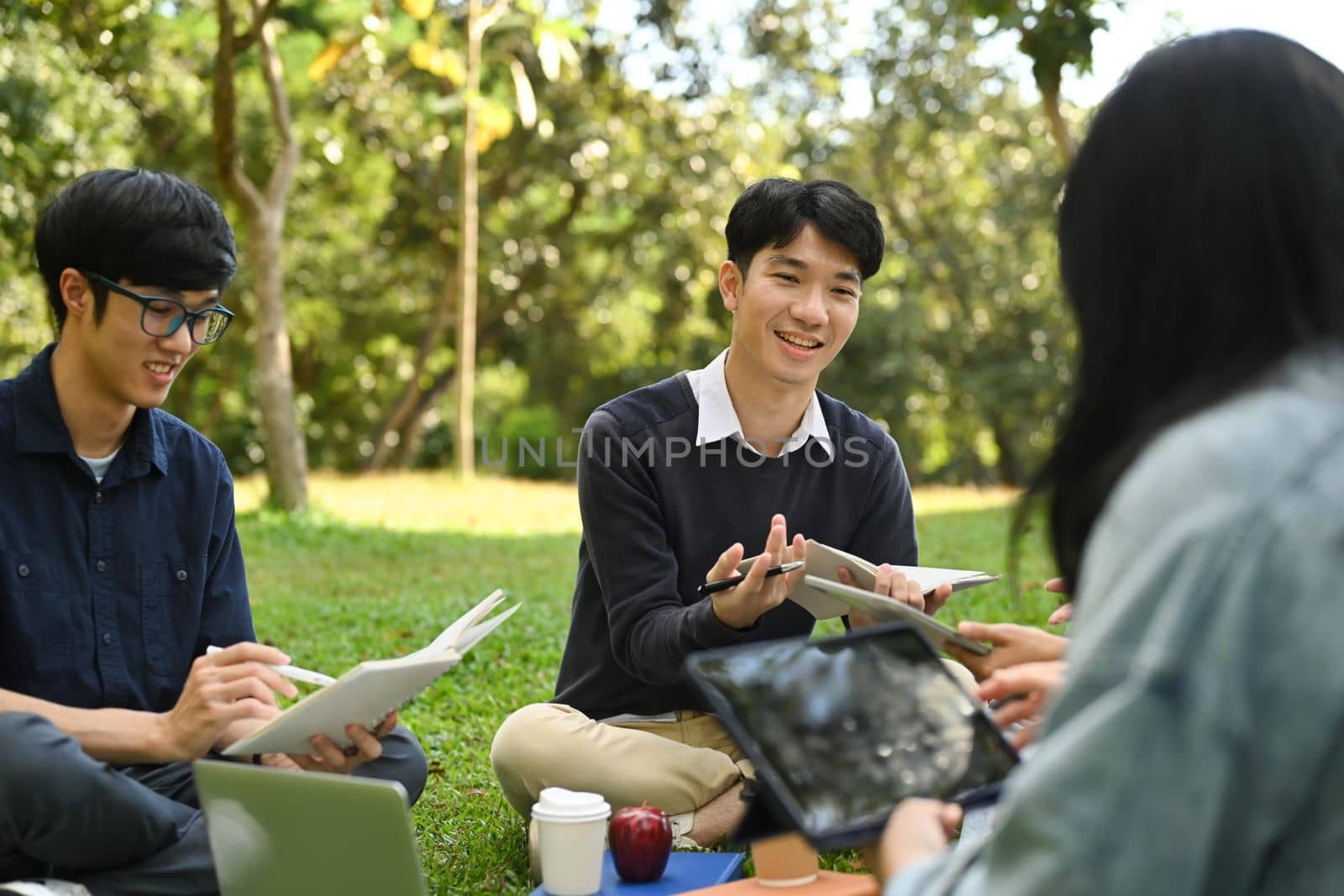 Young Asian college students reading books, preparing for exam while sitting in the campus. Education and lifestyle concept. 