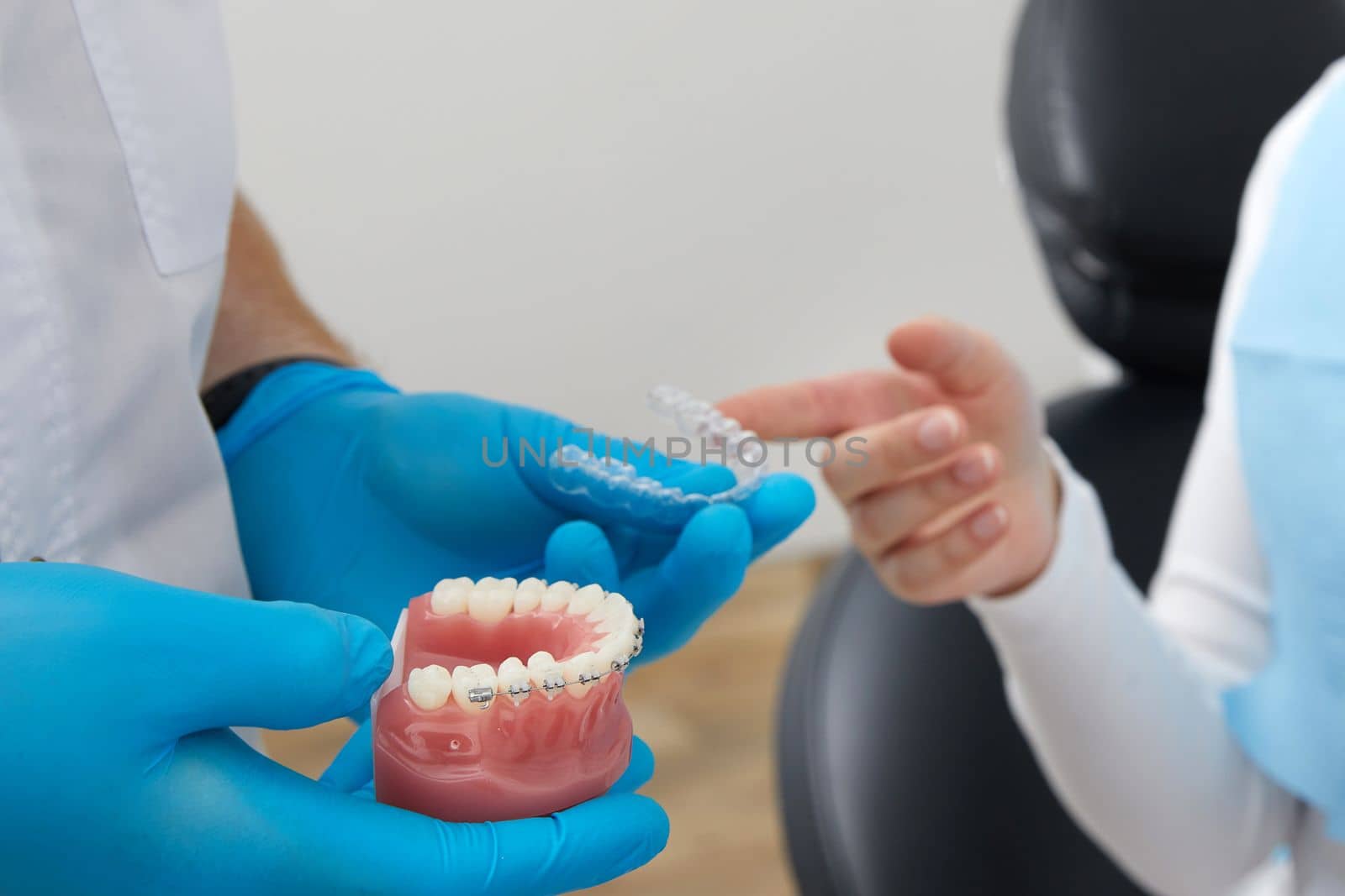 Doctor orthodontist showing model of human jaw with wire braces and aligners explaining difference