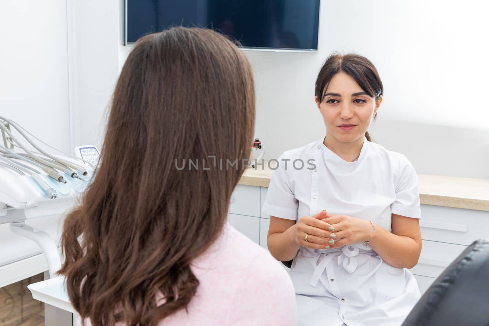 Female dentist explaining patient treatment during an appointment in dental clinic by Mariakray