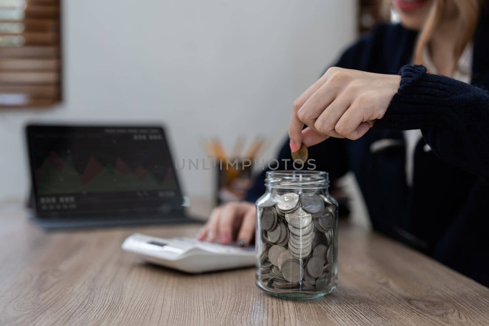 Businesswoman hands carrying a coin put to the saving pocket for her savings idea, calculator, and account.