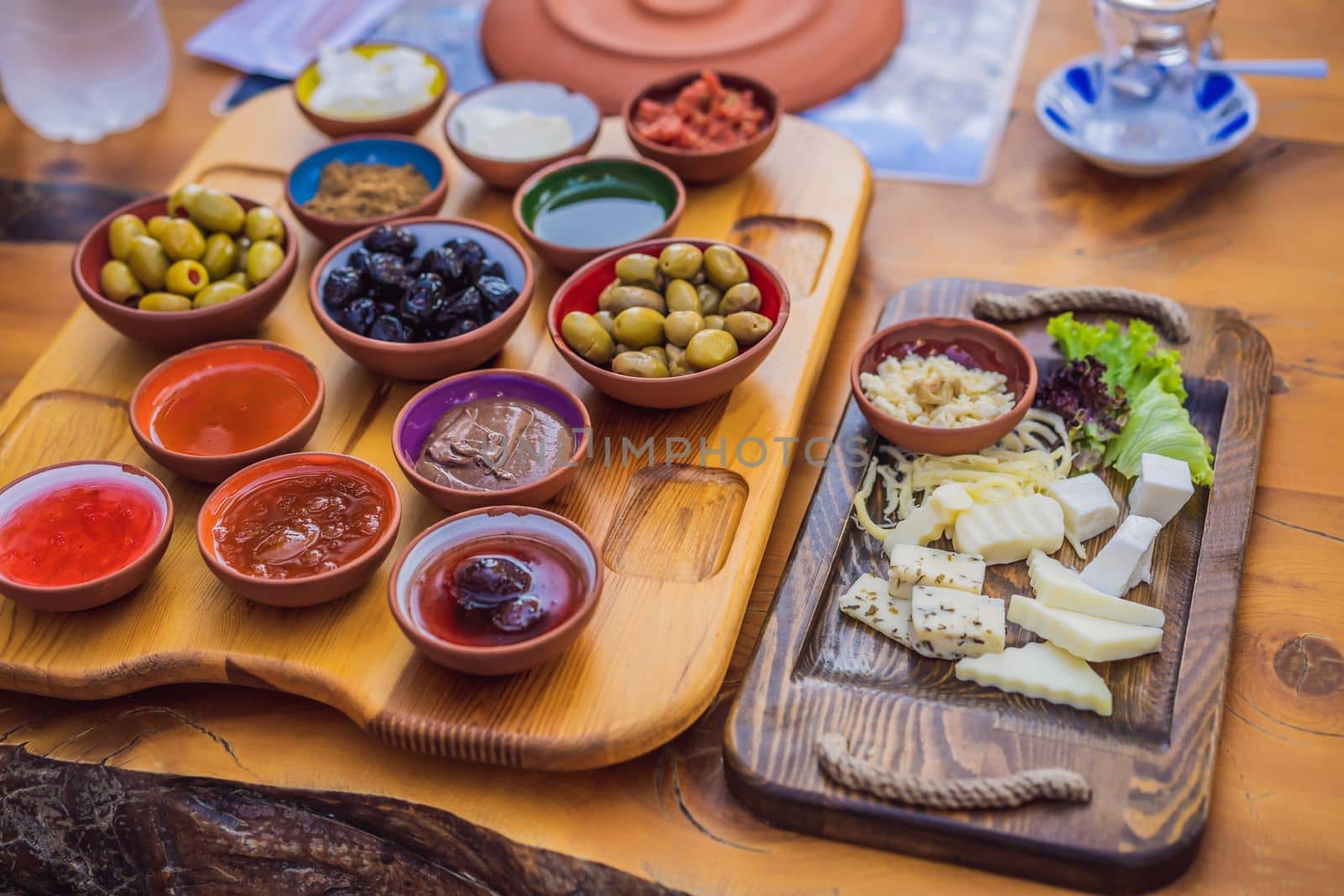 Turkish breakfast table. Pastries. Vegetables. Olives. Cheeses, fried eggs. Jams, tea in copper pot and tulip glasses. Wide composition.