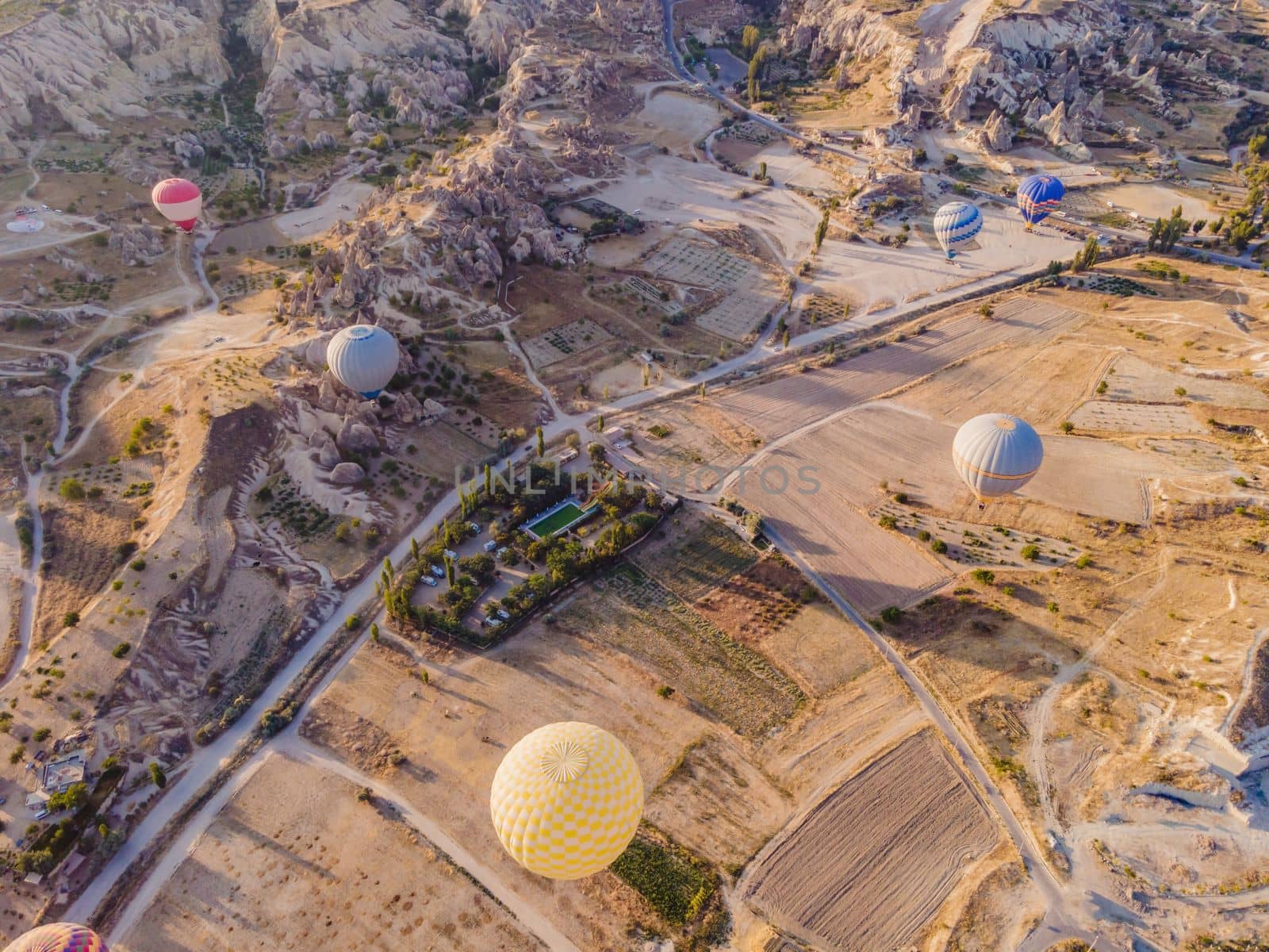 Colorful hot air balloons flying over at fairy chimneys valley in Nevsehir, Goreme, Cappadocia Turkey. Spectacular panoramic drone view of the underground city and ballooning tourism. High quality by galitskaya