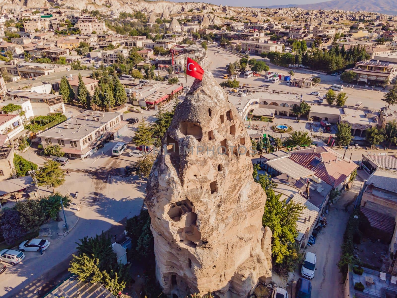 Turkish flag on the hill with typical tuff rock formations of the Cappadocia against the backdrop of a blue sky, Goreme, Turkey.