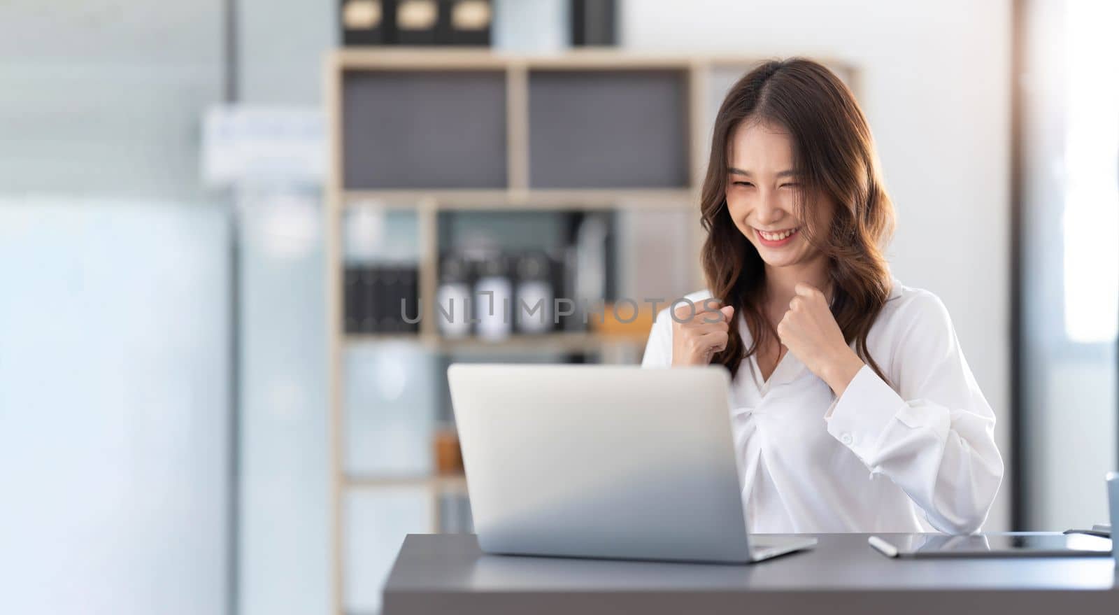 Beautiful asian woman using laptop computer, exciting and celebrating with good news of business successful. Small business startup concept...