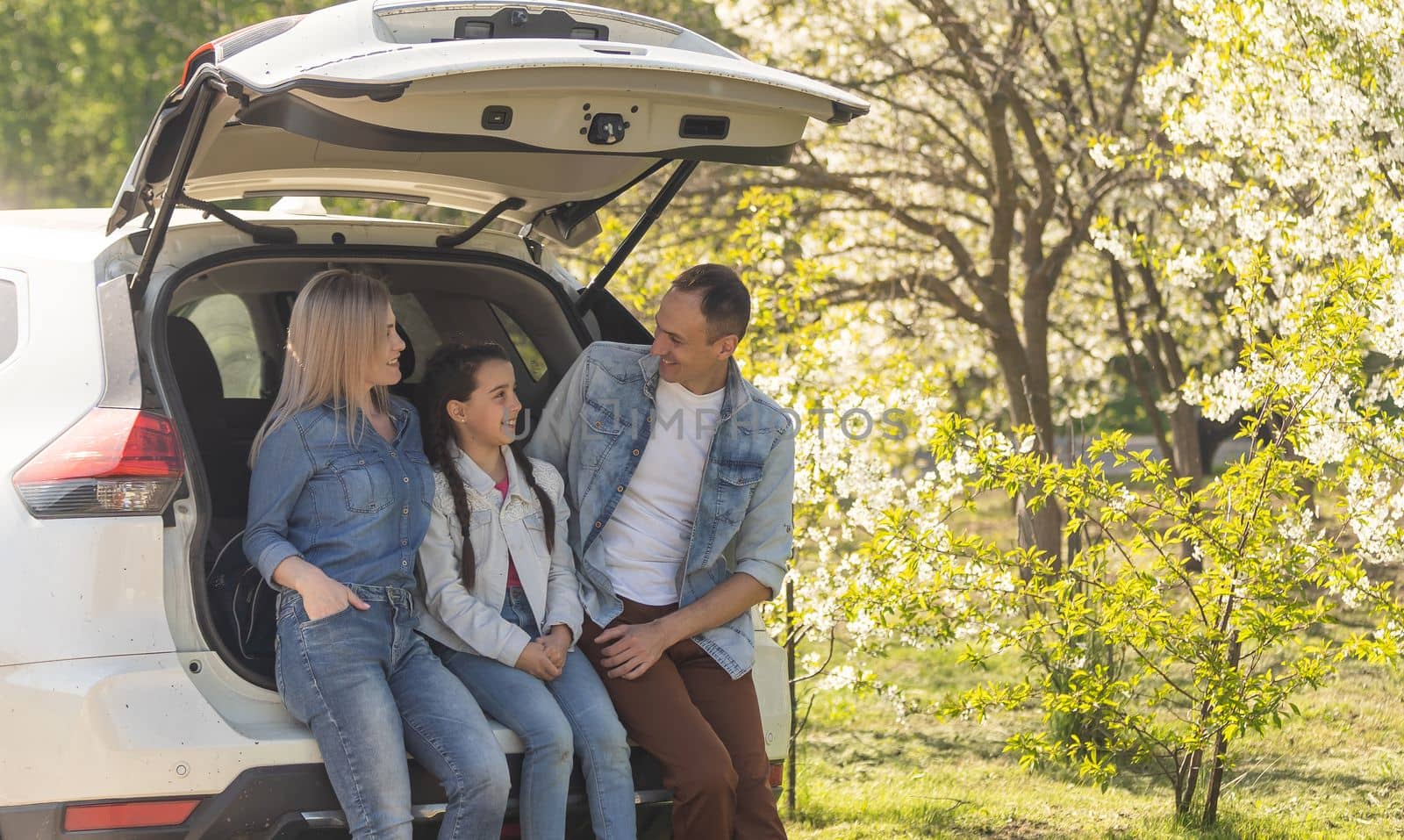 Family with kids sitting in car trunk.