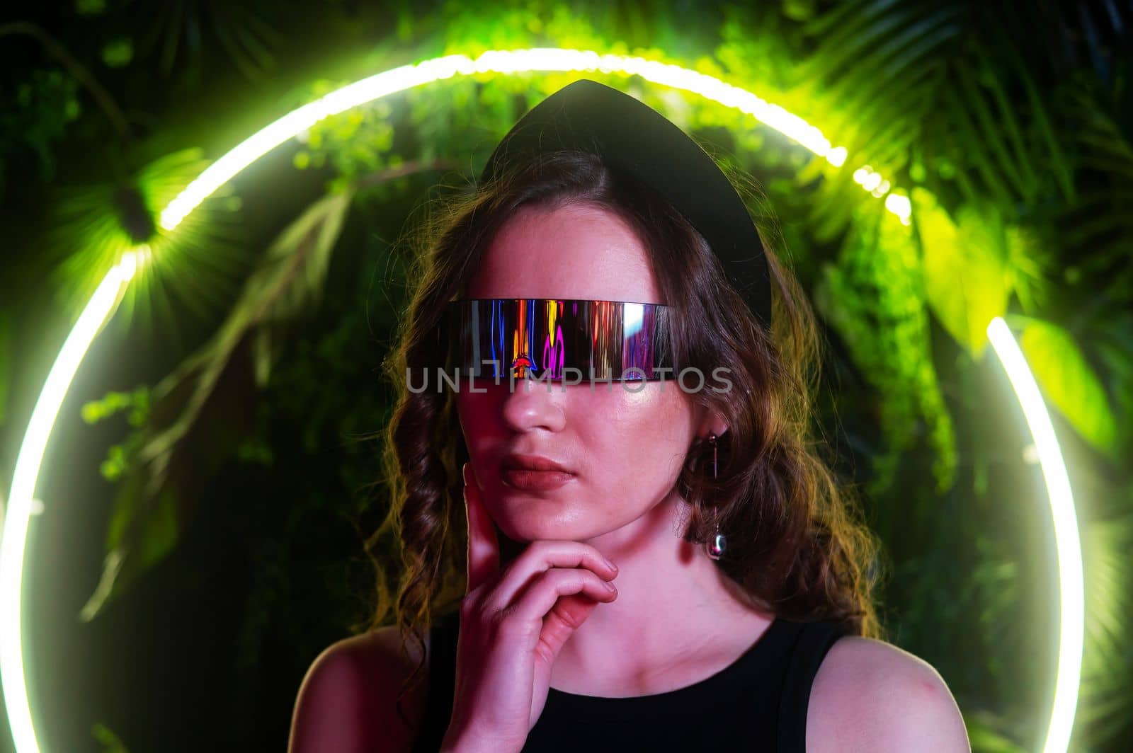 Caucasian woman in panoramic sunglasses against the background of an annular neon lamp in plants