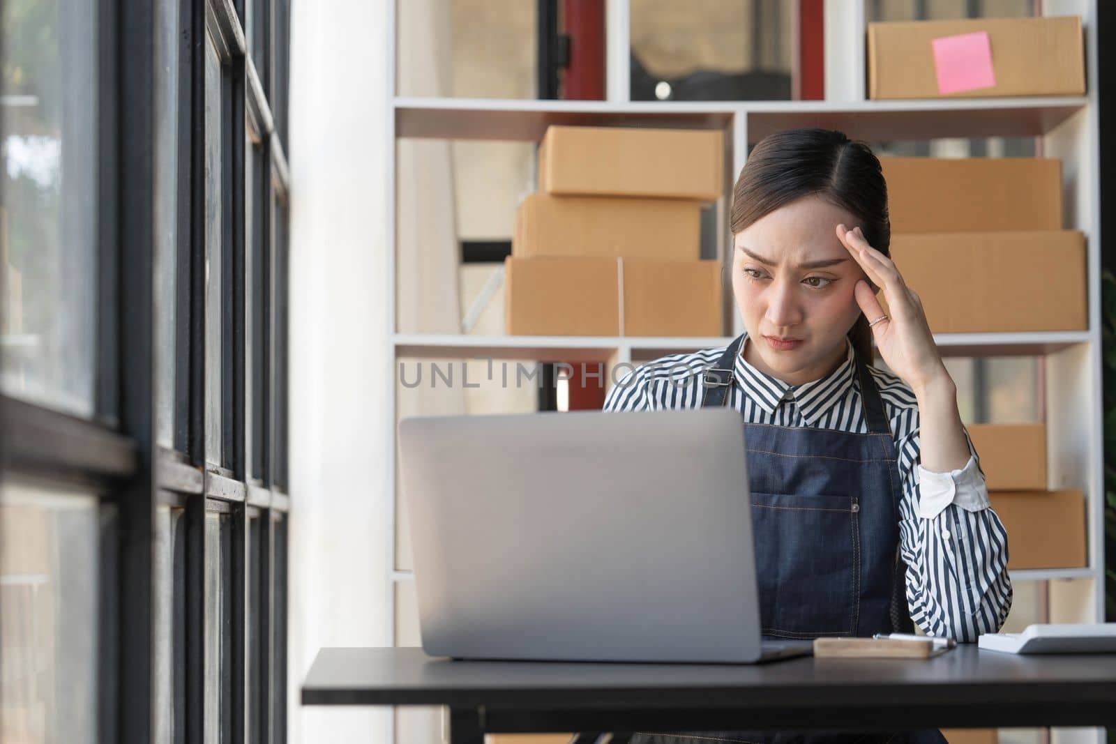 Teenager asian girl freelancer small business serious working at home office with laptop packaging delivery online market on purchase orders to customer