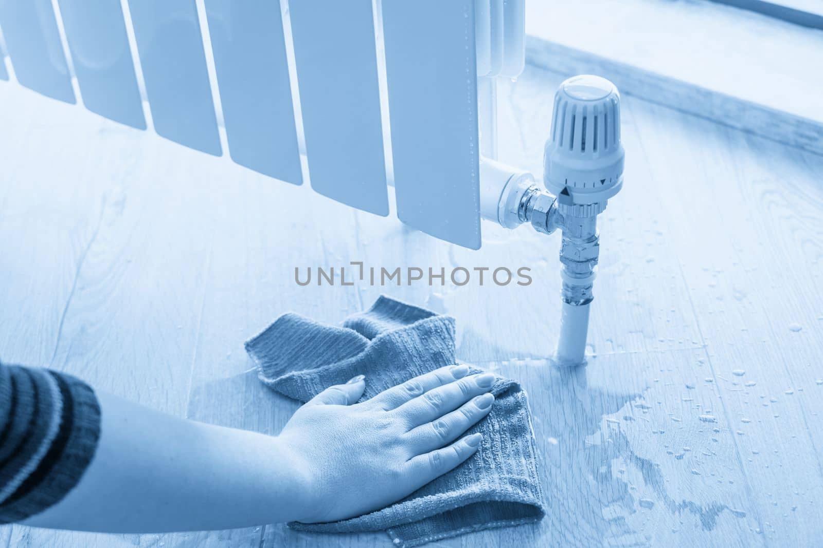 Female hand with rag cleaning water from heating radiator