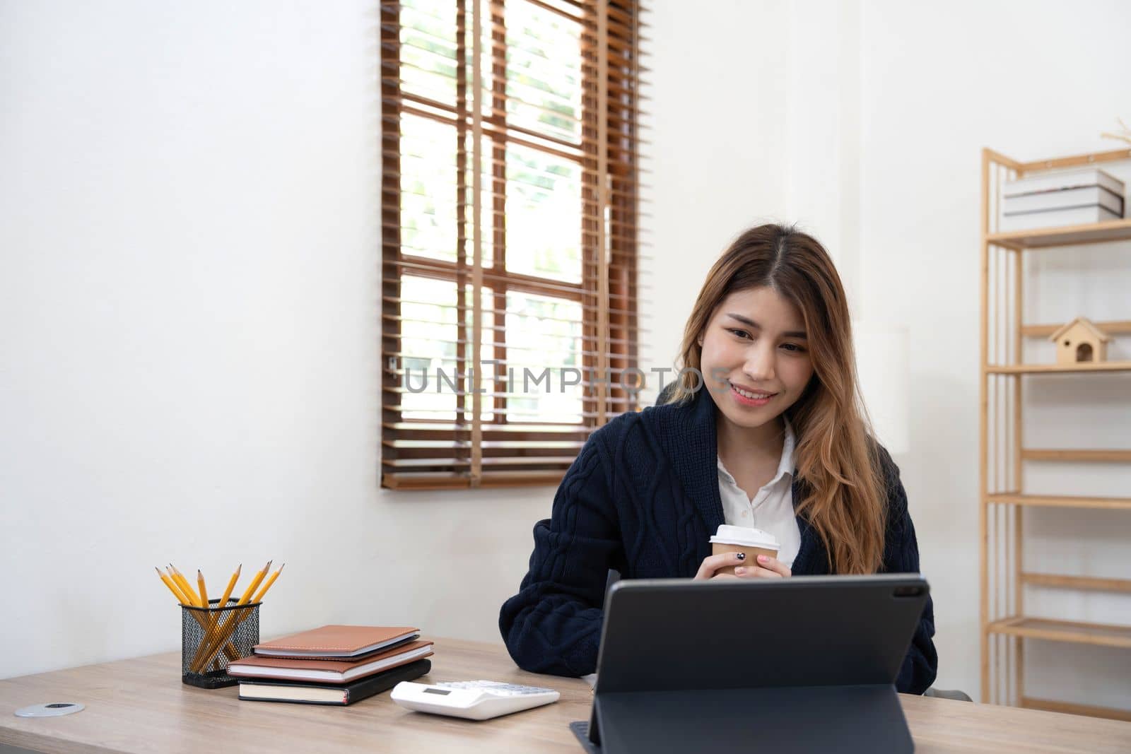 Asian woman Using laptop computer and working at office with calculator document on desk, doing planning analyzing the financial report, business plan investment