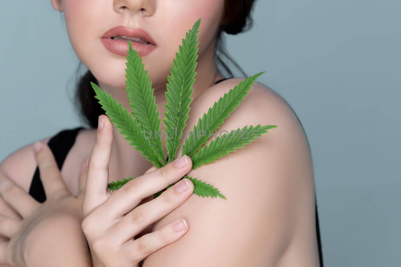 Closeup portrait of charming girl with fresh skin holding cannabis leaf. by biancoblue