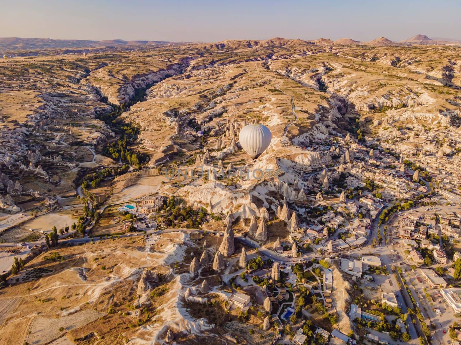 Colorful hot air balloons flying over at fairy chimneys valley in Nevsehir, Goreme, Cappadocia Turkey. Spectacular panoramic drone view of the underground city and ballooning tourism. High quality by galitskaya