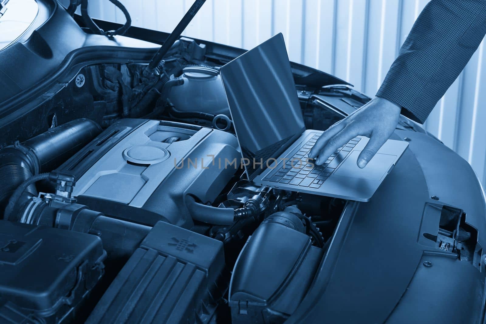 Services car engine machine concept, Automobile mechanic repairman checking a car engine with using computer diagnostics while repairing, car service and maintenance.