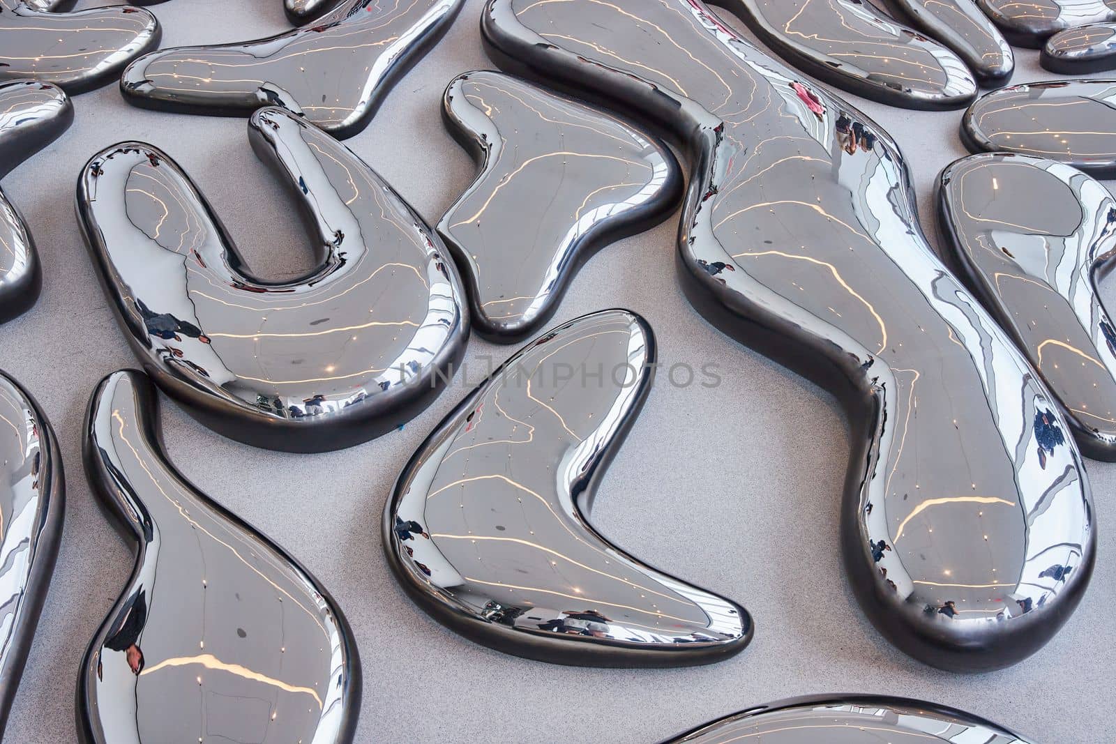 Ground covered in large melted reflecting metal shapes in exhibit by njproductions
