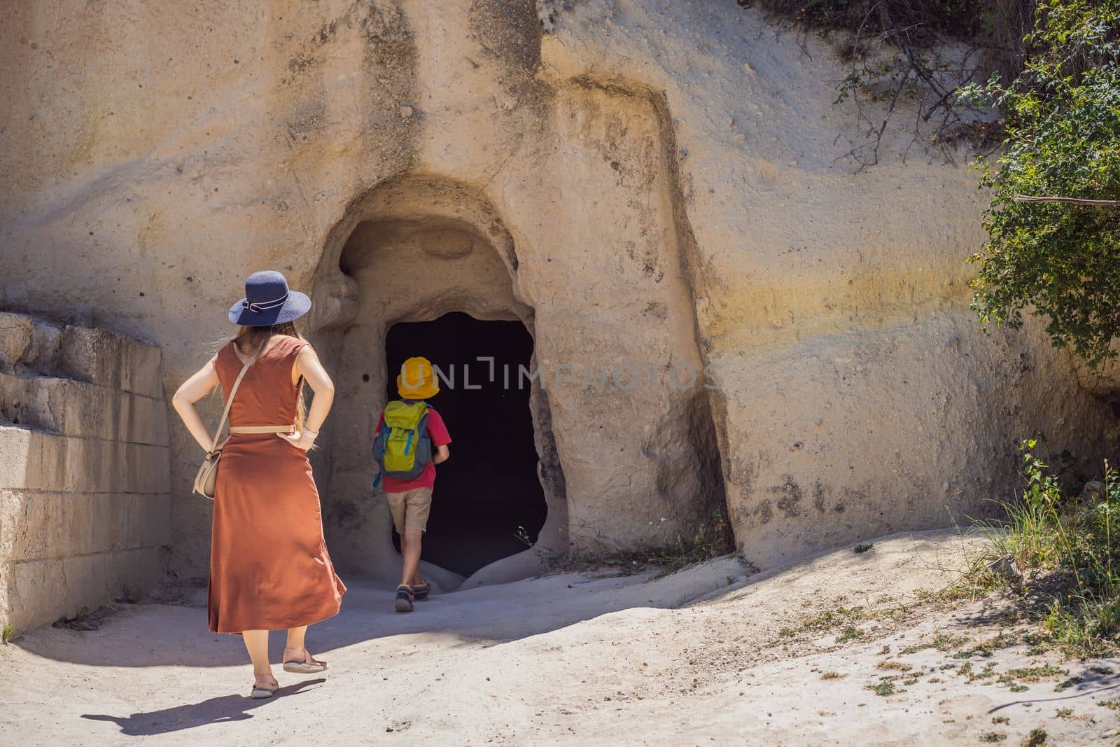 Mom and son tourists exploring valley with rock formations and fairy caves near Goreme in Cappadocia Turkey.