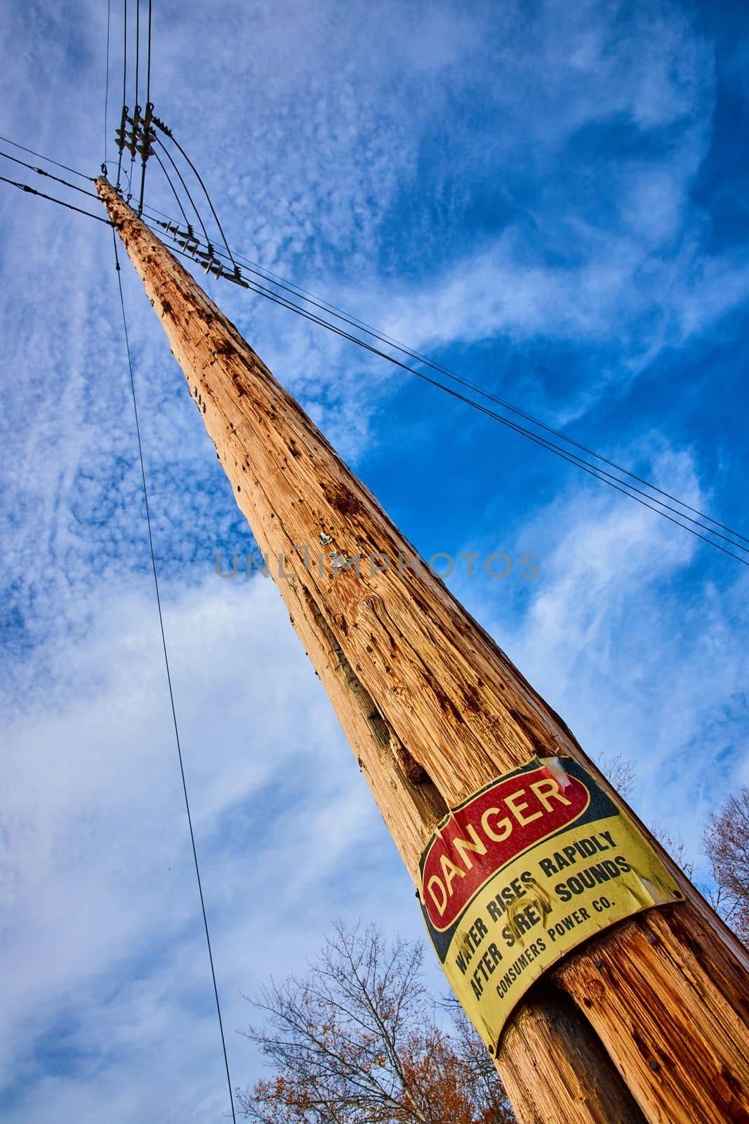 Image of Looking up at telephone pole with large DANGER sign posted about flooding area