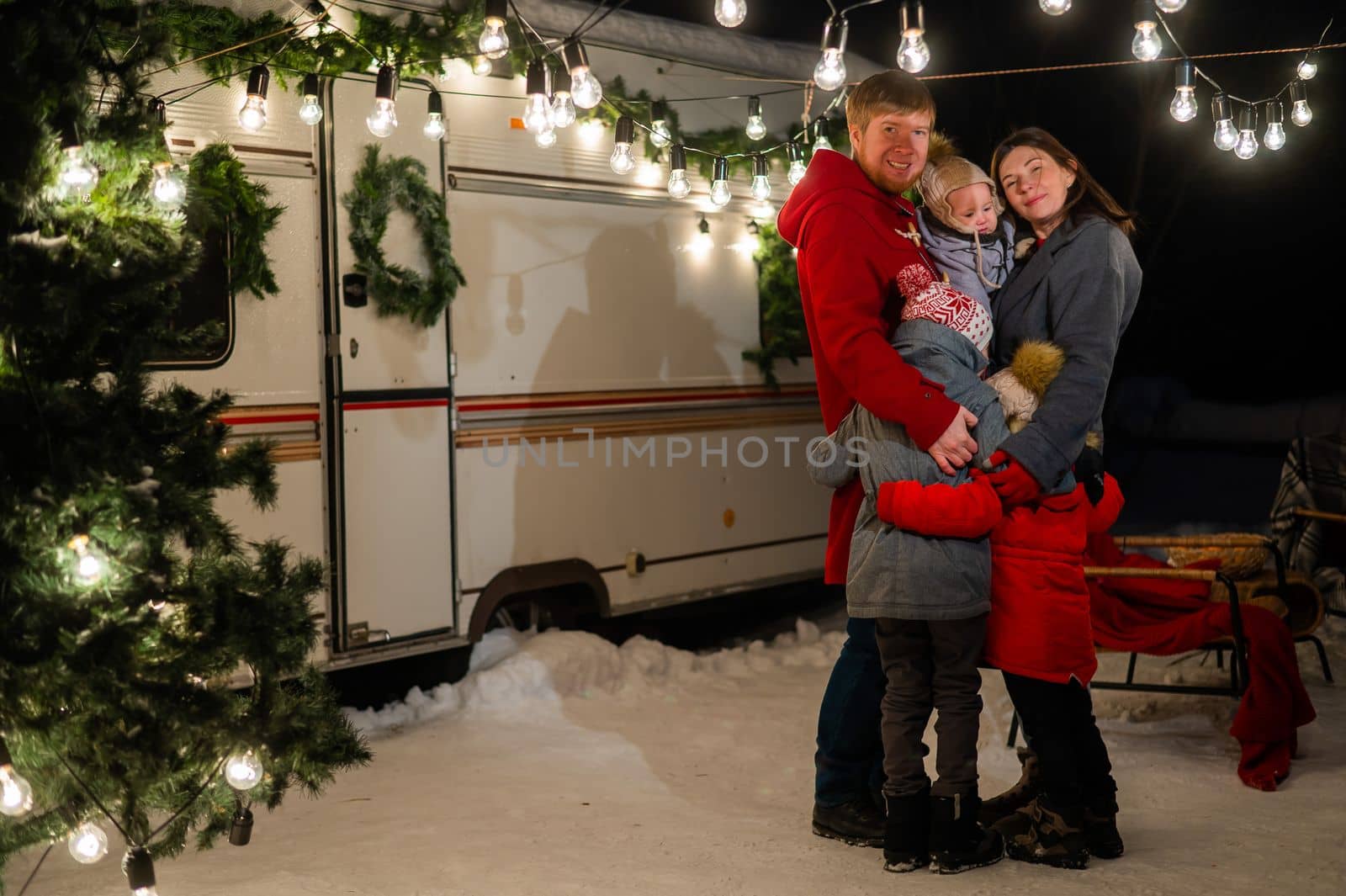 Happy caucasian family hugging outdoors. Christmas decorations. Parents and three sons travel in a camper. by mrwed54