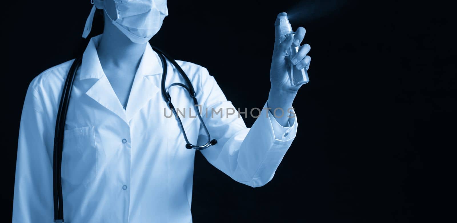 Young female doctor using spray antiseptic spray over black background with copy space by Mariakray