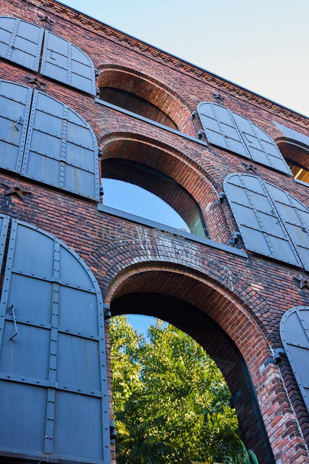 Image of Looking up brick building with arches to woods and dark steel covers