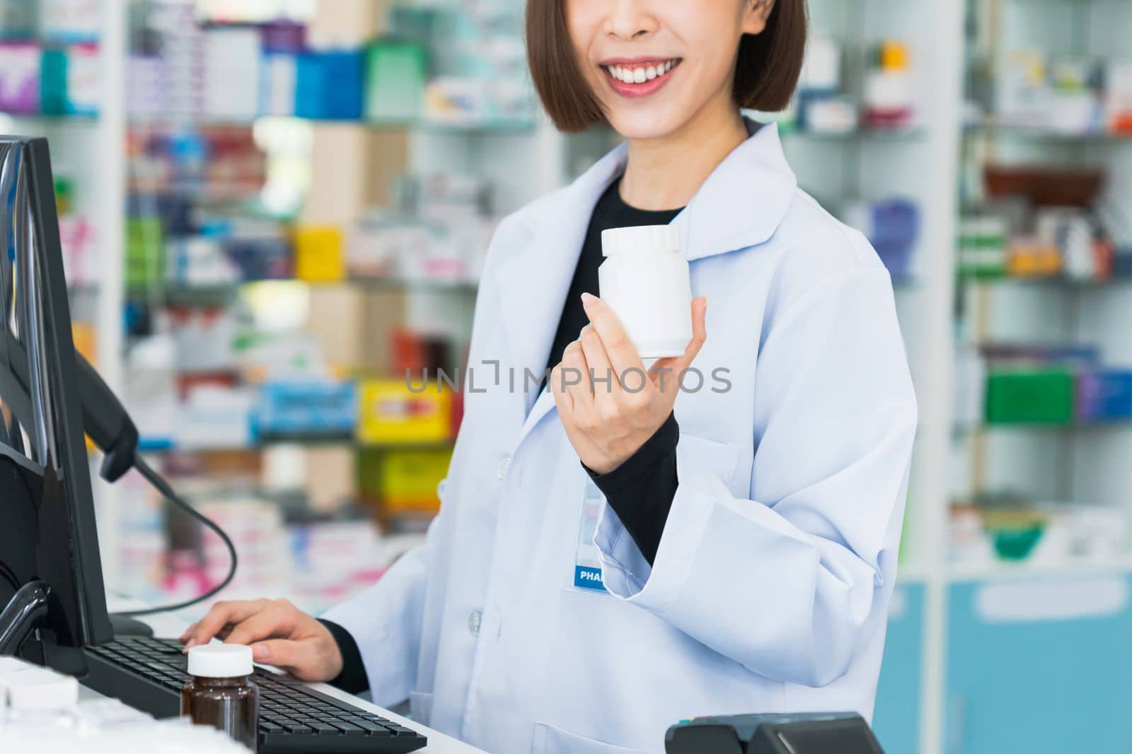 Closeup portrait of young asian pharmacist pill bottle at qualified pharmacy. by biancoblue