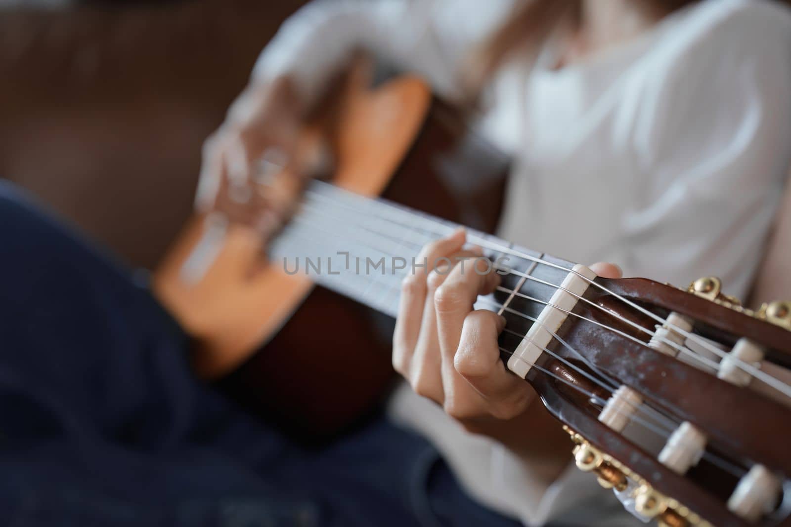 Portrait of young asian woman playing guitar on sofa relaxing stress on vacation by Manastrong