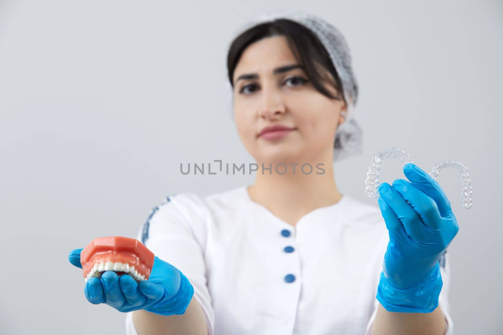 Doctor orthodontist showing model of human jaw with wire braces and aligners explaining difference