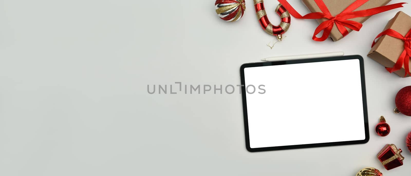 Digital tablet, gift boxes and Christmas ornaments on white background. Top view with copy space for your advertise text.