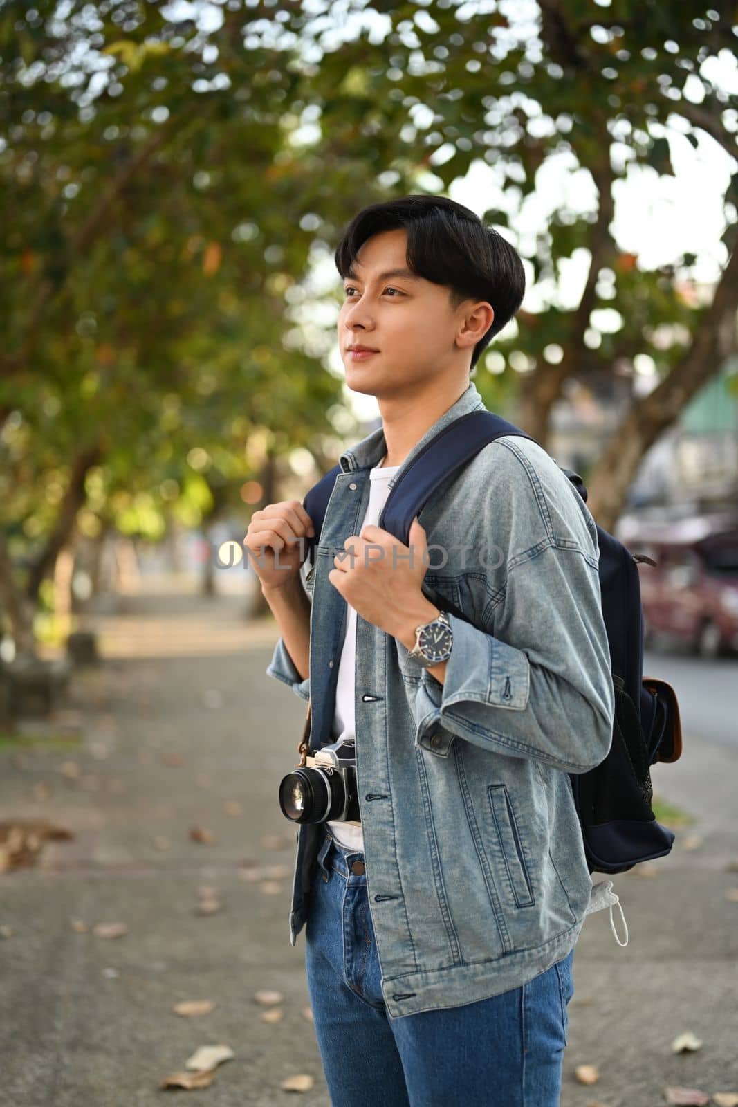 Happy asian man traveller in hipster outfit spending free time outdoors, walking in the city street on beautiful day.