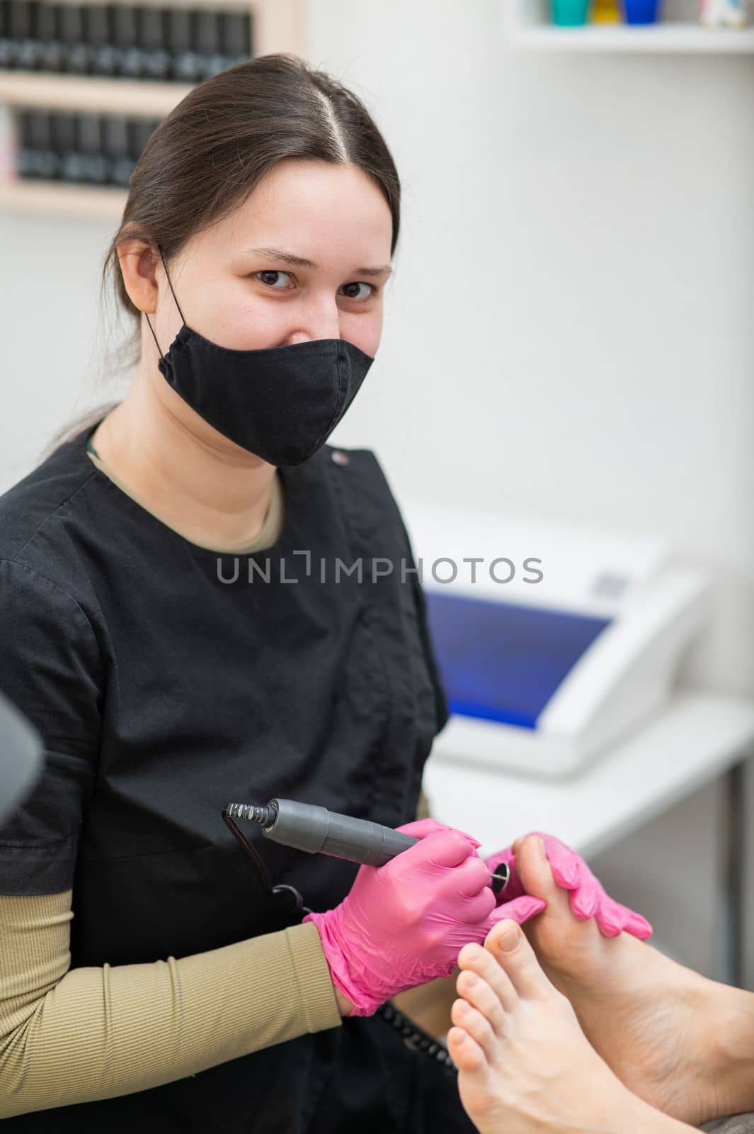 The pedicure master processes the client's foot using an apparatus with an abrasive disc. by mrwed54