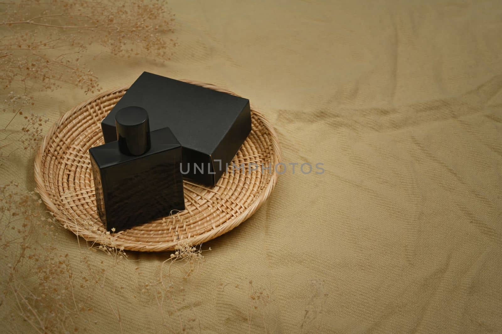 Mockup of fragrance perfume bottle on round rattan basket. Products design and branding concept.