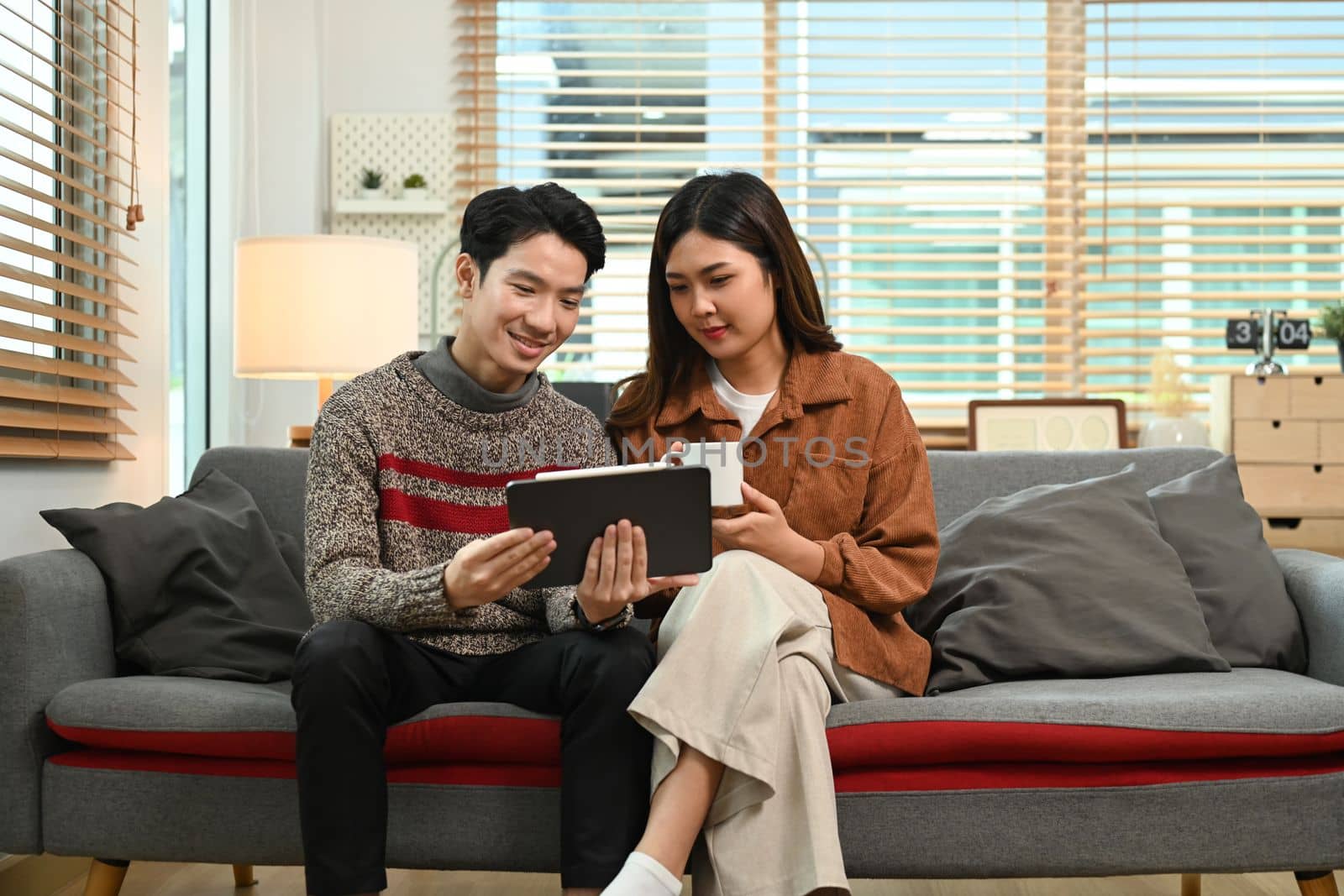 Young asian couple using digital tablet, enjoy spending time together on winter holidays by prathanchorruangsak