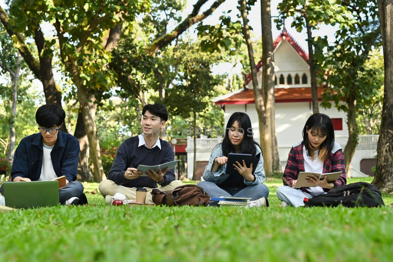 Group of students doing group project and reading book together in university campus. Education and youth lifestyle concept by prathanchorruangsak