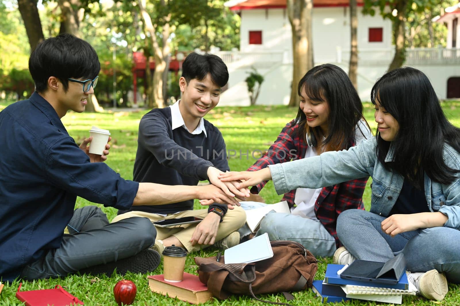 Group of university students stacking hands together. Relationship, youth and community concept by prathanchorruangsak