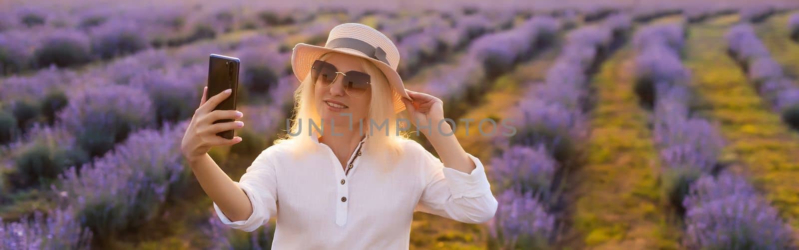 Young blond woman traveller wearing straw hat in lavender field surrounded with lavender flowers