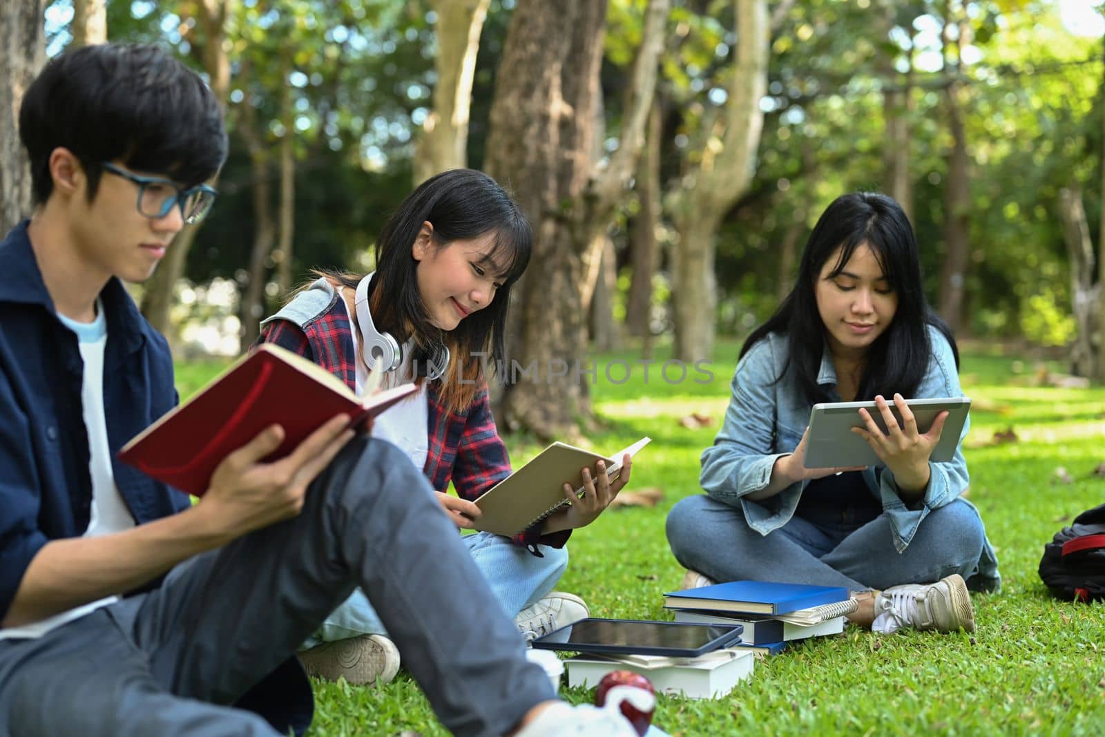 Young college students reading books, preparing for exam while sitting in the campus. Education and lifestyle concept by prathanchorruangsak