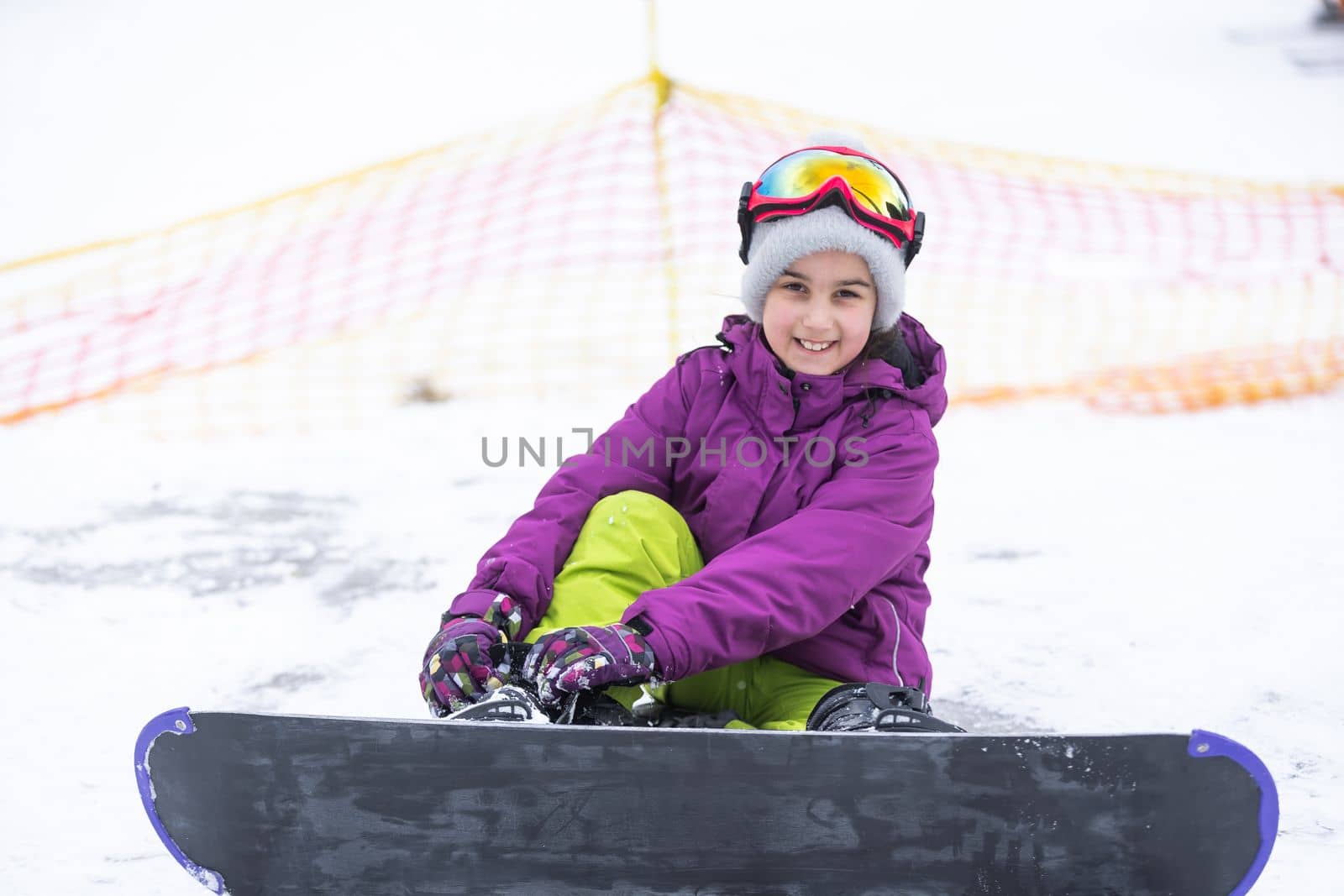 Little Cute Girl Snowboarding at ski resort in sunny winter day
