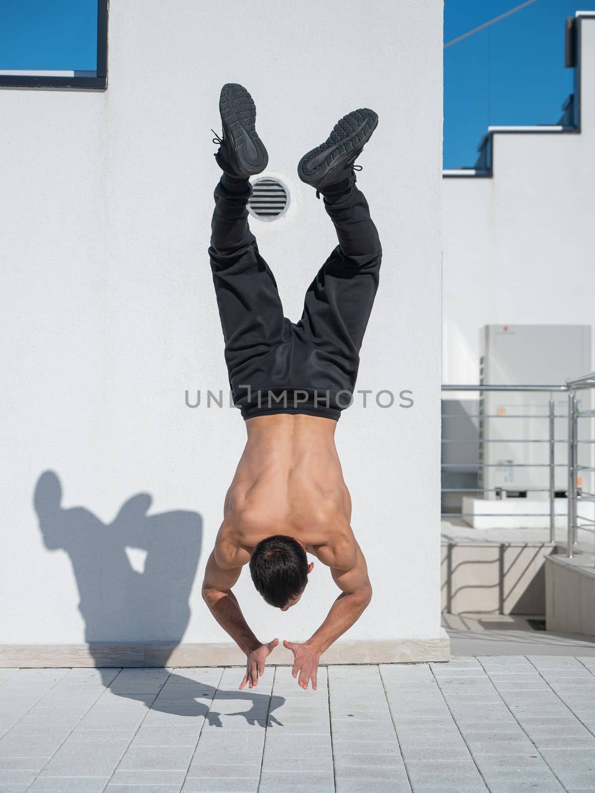 Man doing a handstand outdoors against a white wall. by mrwed54