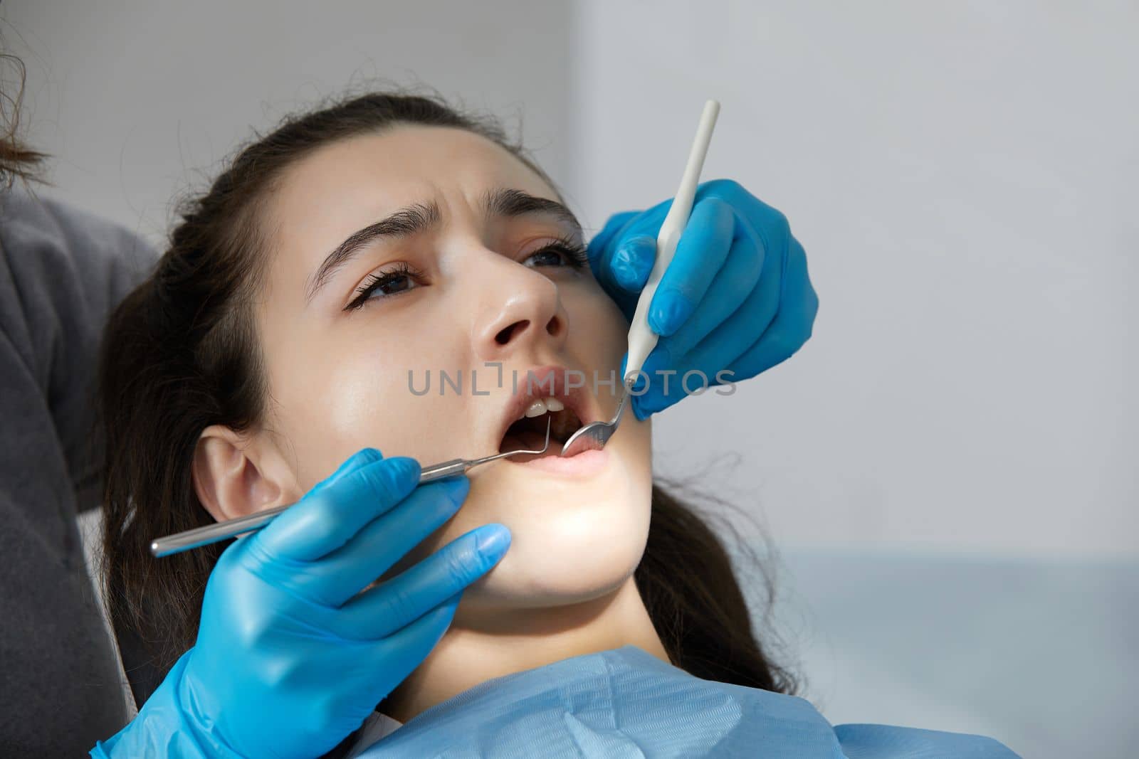 Dentist checking teeth of a female patient with dental mirror by Mariakray