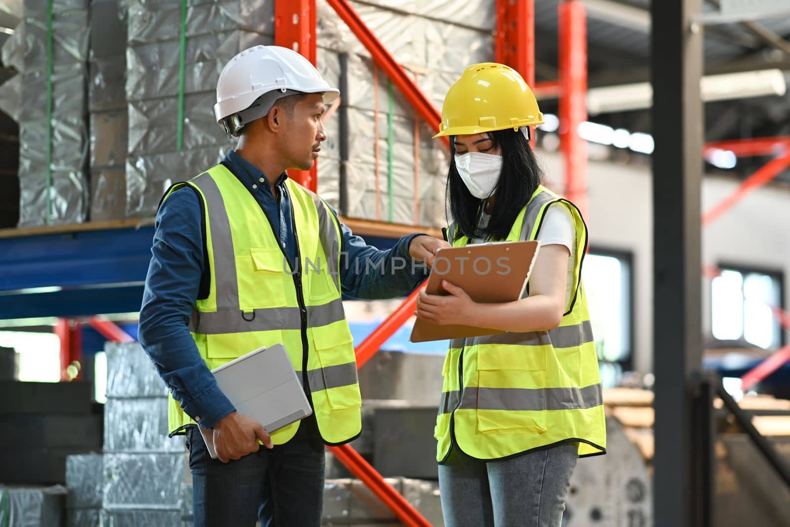 Warehouse workers are working in the retail warehouse full of shelves with goods. Manufacture storehouse occupation concept.