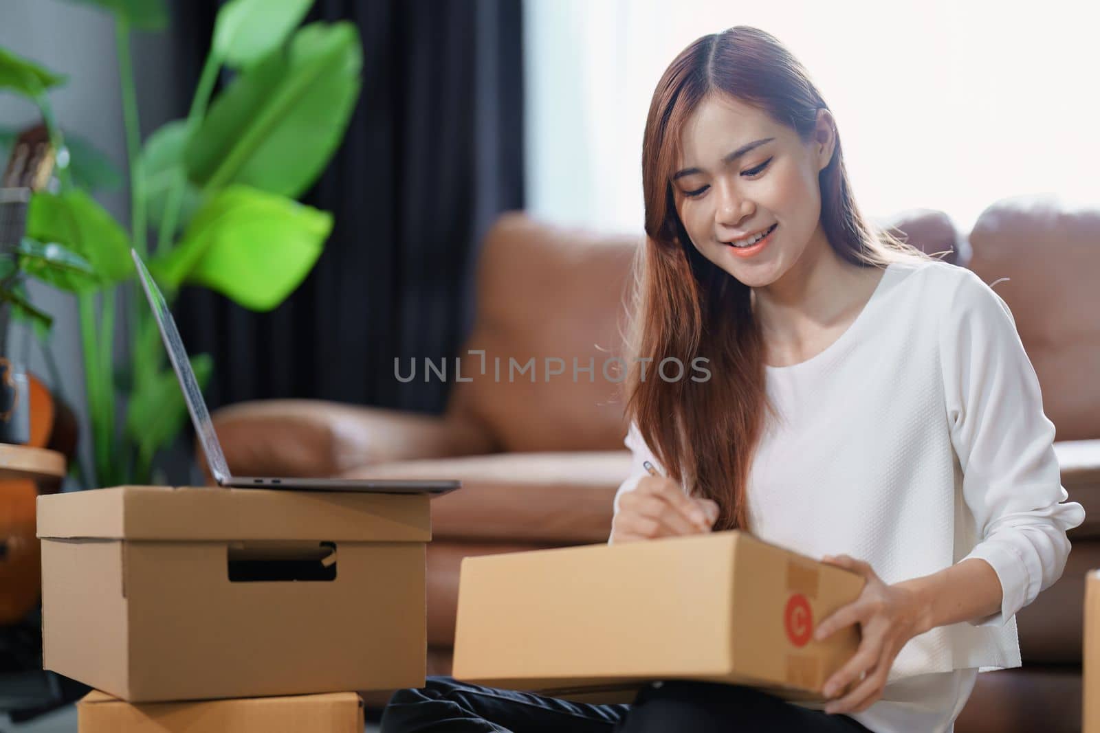 Starting small business entrepreneur of independent Asian female online seller packing products to send to customers and SME delivery concept by Manastrong