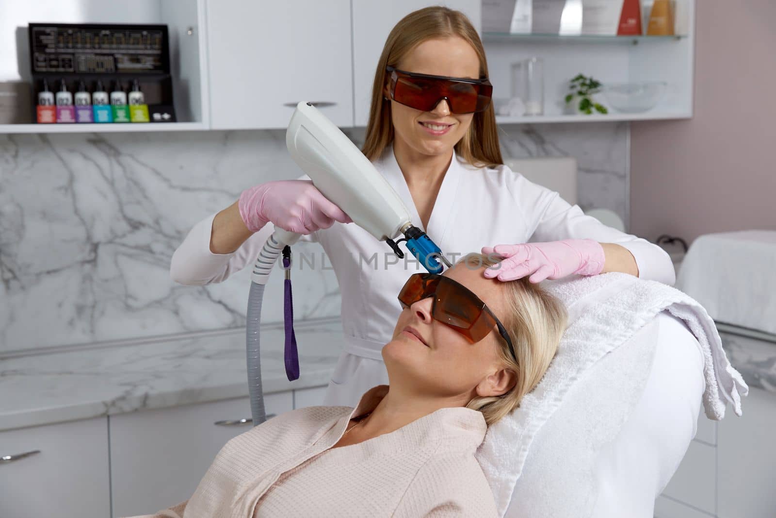 Woman receiving laser treatment in modern cosmetology clinic by Mariakray
